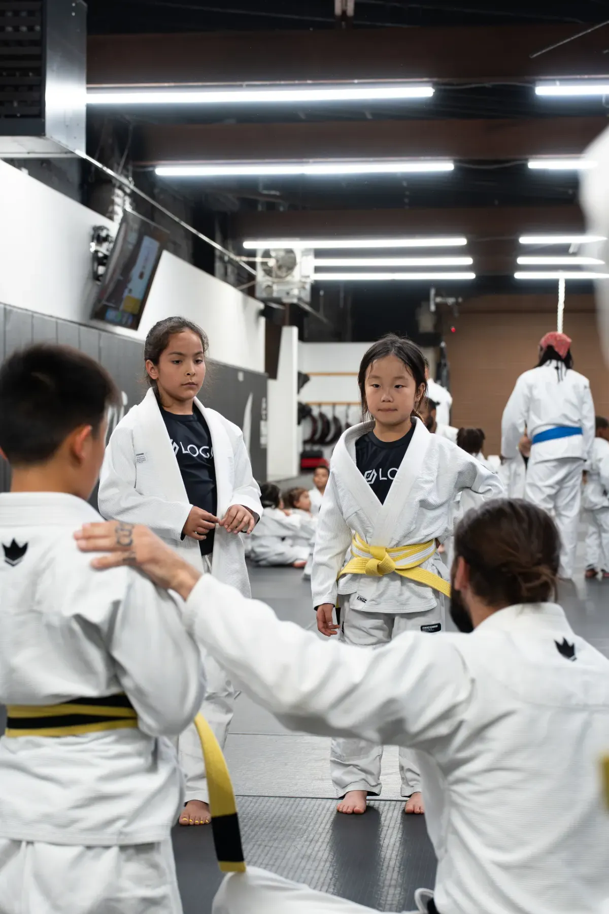 Kids in white gis lined up bowing in to their black belt coach before Jiu Jitsu class