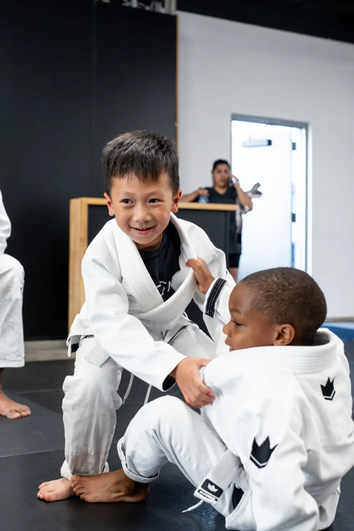 Two smiling kids grappling together during partner drills at Logic Jiu Jitsu