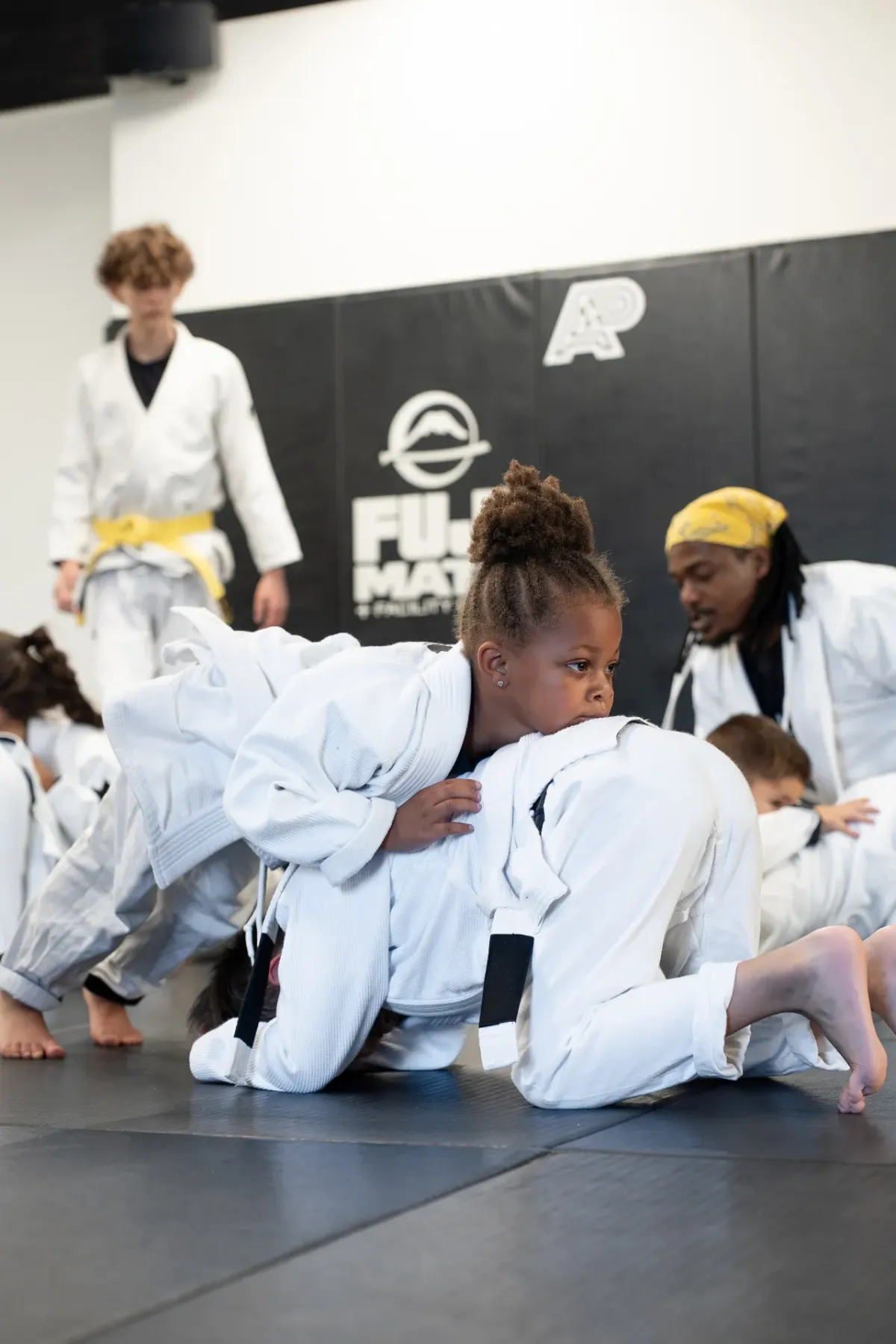 A young girl drilling turtle position defense during Logic's kids Jiu Jitsu class